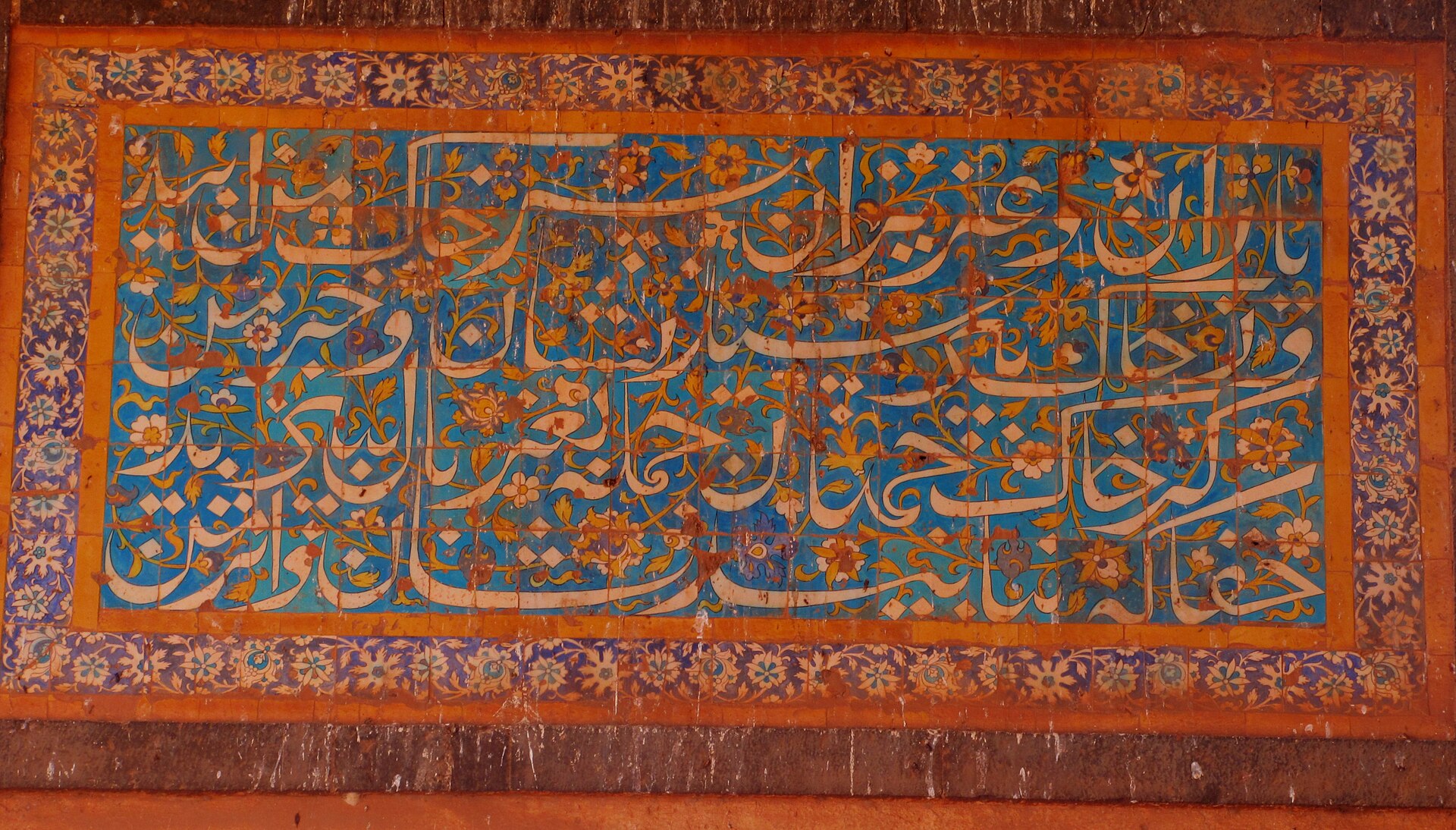 Frescoed calligraphy at wall Tomb of Ali Barid Shah. Inside of the dome is laid with colored tiles with verses of Quran written in Persian. Each corner of the dome is carved with exquisite carvings on plaster and is a delight to watch. The inner walls are also fitted with colored tiles It is quite extraordinary that this inner beauty has withstood hundreds of years of weather considering the fact that it is open on all sides.