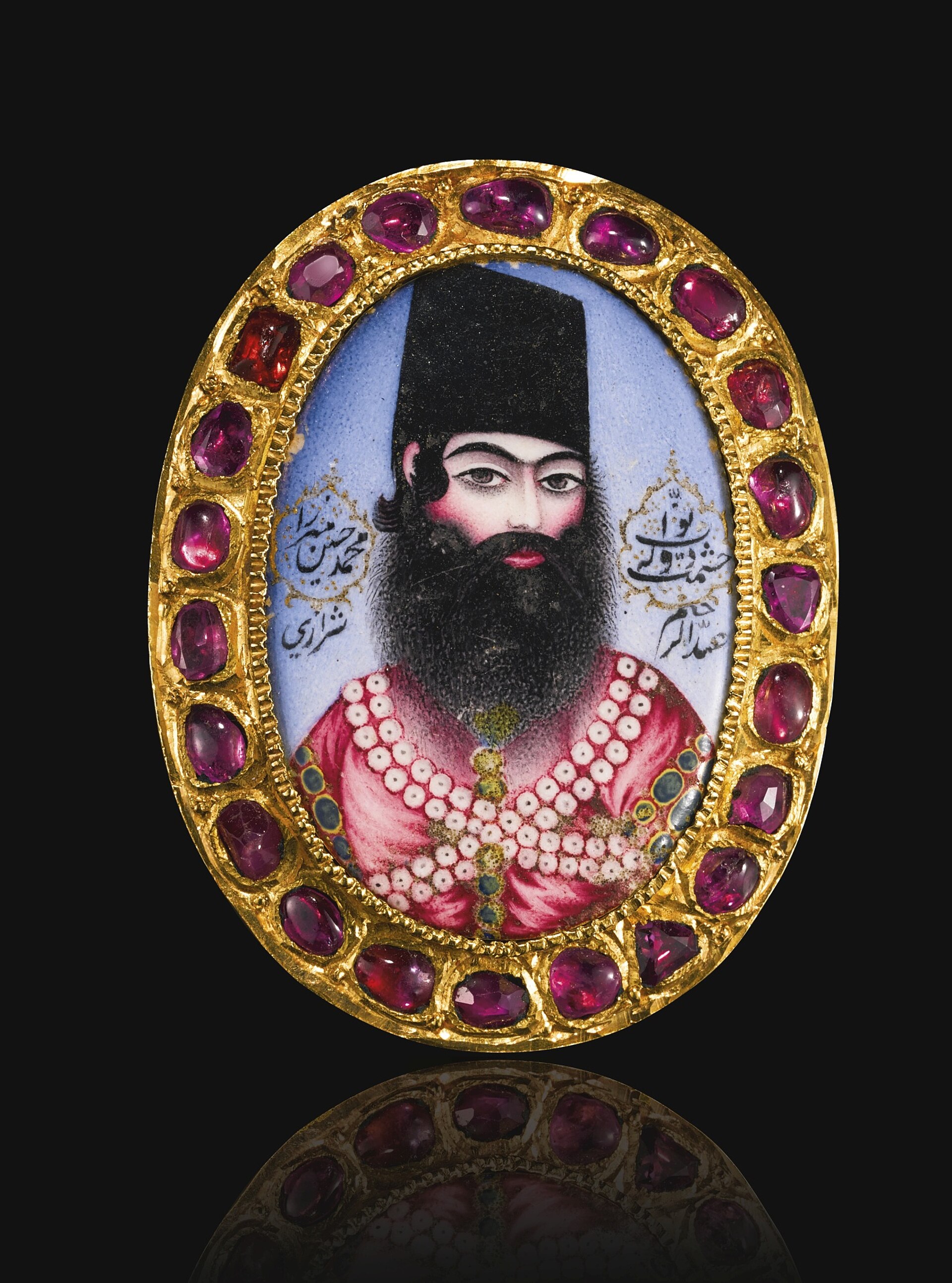 A Qajar enamelled and gem-set portrait medallion of Muhammad Husayn Mirza Hishmat al-Dawlah, Persia, early 19th century Enamelled and gem-set 4.6cm. height 3.6cm. diam. Featuring a portrait of prince Muhammad Husayn Mirza Hishmat al-Dawlah (d.1845-46 AD) with inscriptions, set within a fine gold frame mounted with rubies Inscriptions: ‘Navvab Hishmat al-Dawlah Muhammad Husayn Mirza/ Work of … Shirazi Muhammad Husayn Mirza Hishmat al-Dawlah was the eldest son of Muhammad ‘Ali Mirza Dawlat-shah and a grandson of Fath ’Ali Shah Qajar. He was appointed Governor of Kermanshah in 1821-2, and received the title Hishmat al-Dawlah after his victory over the Ottomans in 1822-3. He was among the eleven princes who rebelled after Fath’ali Shah’s death and were exiled and imprisoned in Ardabil in 1835 AD. He was later moved to Tabriz where he died in 1845-6 (M. Bamdad, Dictionary of National Biography of Iran, 1700-1960, vol. 3, pp. 375-6).