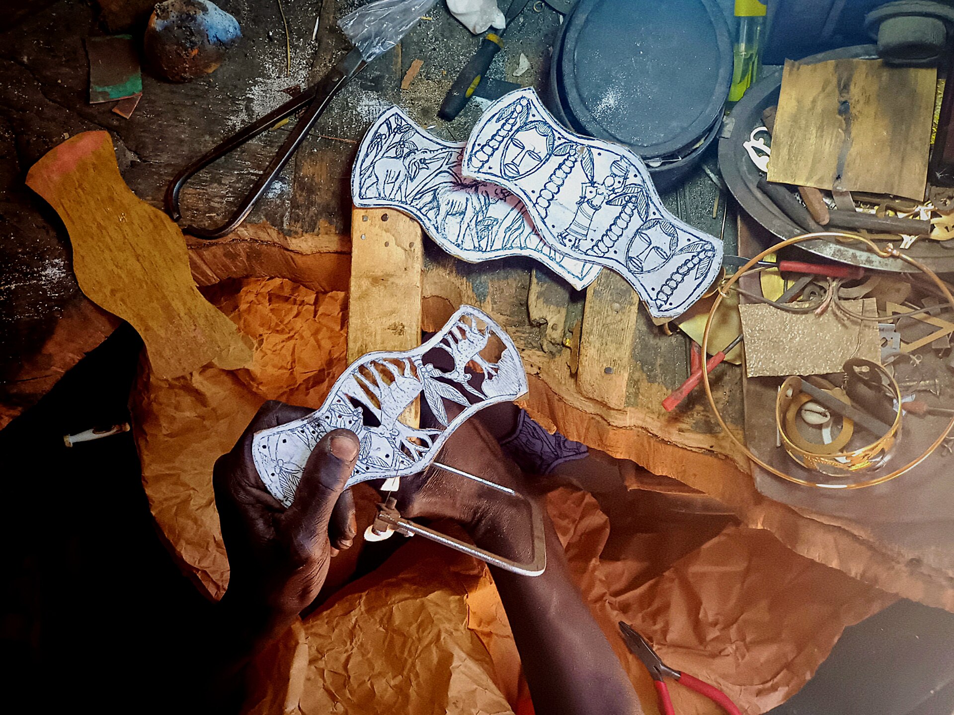 In the artisanal village of Soumbedioun in Senegal, there's a skilled metalworker who makes beautiful decorative accessories. He cuts metal boards with care to create unique pieces for homes. His workshop is busy with the sound of metal being shaped. Drawing inspiration from his culture, he uses both old and new techniques to craft each accessory with precision. Through his art, he keeps alive the traditions of Soumbedioun while adding beauty to everyday life.