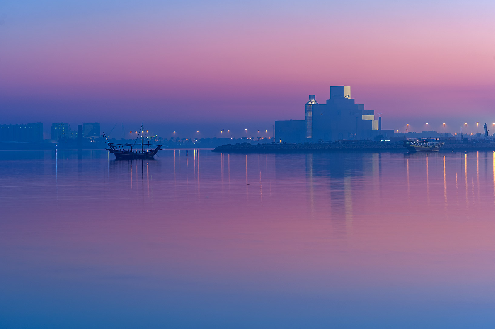View of the Persian Gulf and the Museum of Islamic Art in Qatar at dusk.