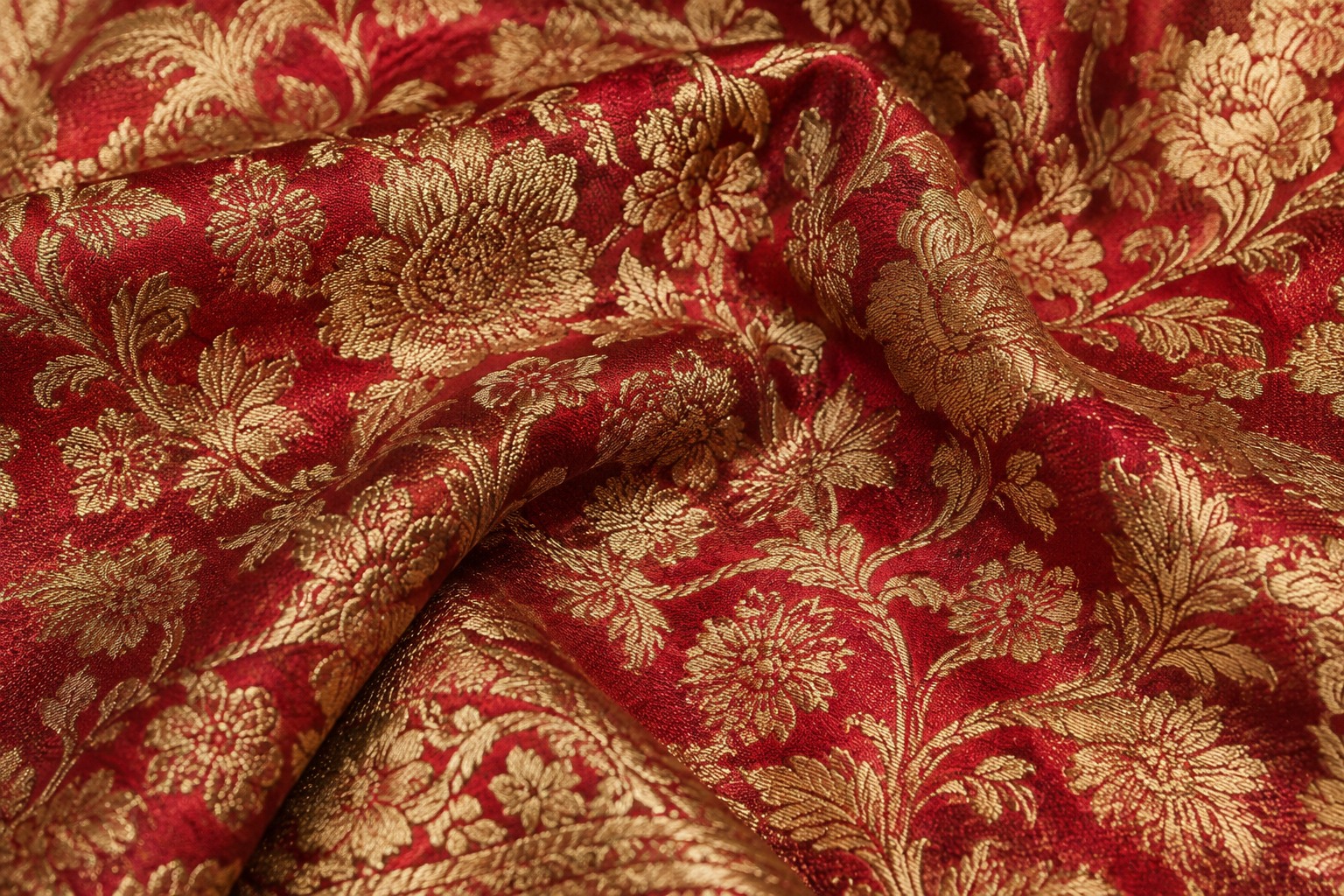 Illustration of crimson brocade folded to reveal dense gold floral patterns and woven texture.